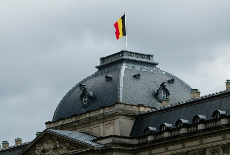 gray and white building with red, yellow, and black striped flag on roof