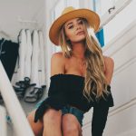 woman in black off-shoulder shirt sitting on brown wooden stairs